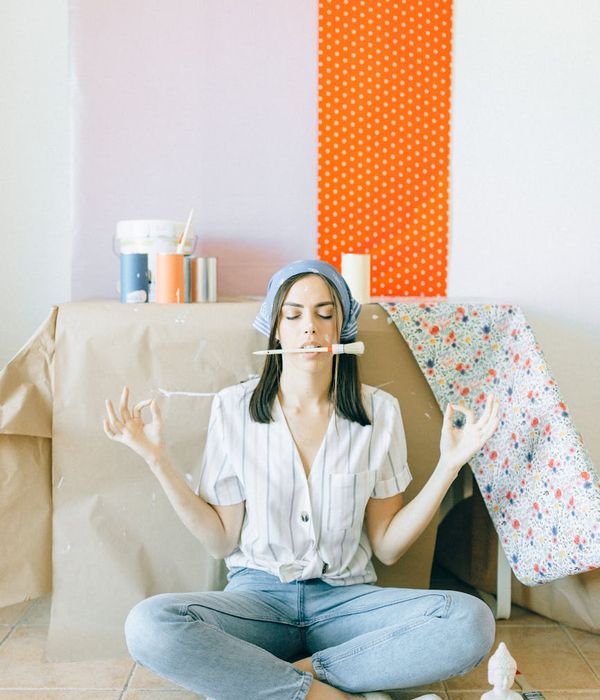 Person meditating in a bright, clean room with a small plant in the background.