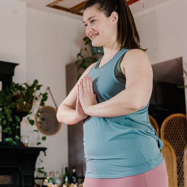 Woman smiling peacefully while doing a gentle stretching exercise in her living room.